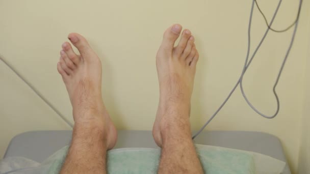 Женщина-врач прикрепляет контакты к ногам пациентов. — стоковое видео