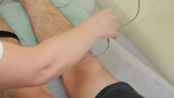 Kvindelig læge lægger kontakter til patientens ben. – Stock-video
