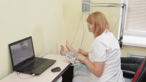 Woman doctor examines a patient with a device for measuring nerve impulses. — Stock Video