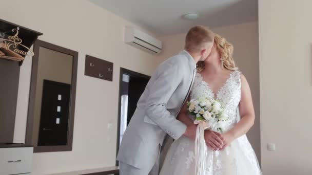 El novio guapo en la habitación besa a la novia. — Vídeo de stock