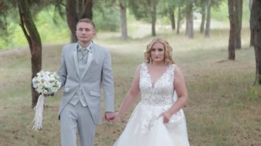 Çok güzel gelin ve damat yazın ormanda yürüyor..