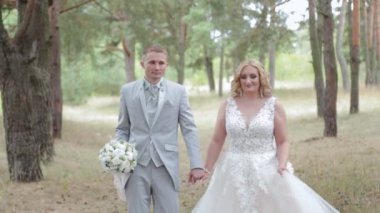 Çok güzel gelin ve damat yazın ormanda yürüyor..