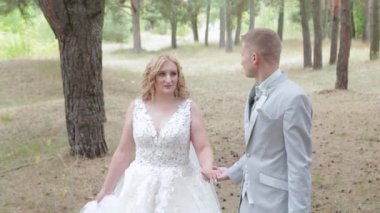 Çok güzel gelin ve damat yazın ormanda yürüyor..