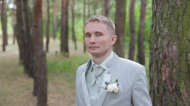 Ağacın yanındaki ormanda yaka çiçekli yakışıklı damat..