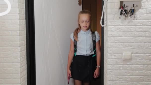 Vacker flicka går in i lägenheten efter skolan med en portfölj. — Stockvideo