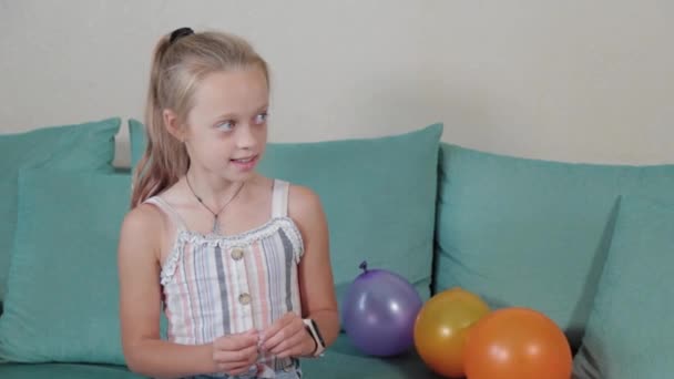Chica feliz estallando globos en el apartamento. — Vídeo de stock