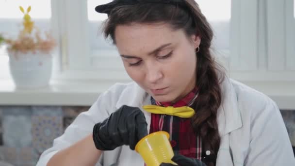 Молодая женщина проводит химические эксперименты дома. — стоковое видео