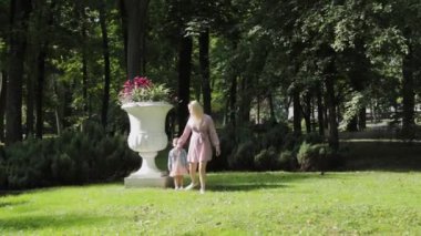 Genç anne ve kızı parkta yürüyorlar..