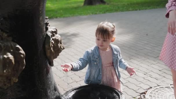 Meisje bij de drinkfontein in het park. — Stockvideo