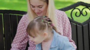 Parkta kollarında küçük kızı olan genç bir anne..