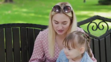 Parkta kollarında küçük kızı olan genç bir anne..