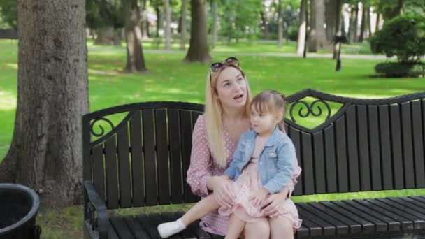 Ung mor med liten dotter i famnen i parken. — Stockvideo