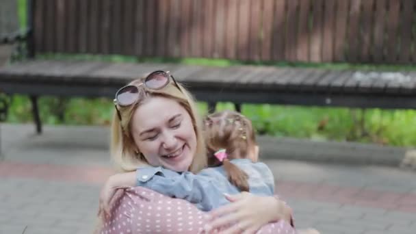 Feliz madre joven con hija pequeña cerca del macizo de flores en el parque. — Vídeos de Stock