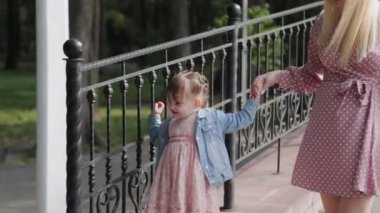 Küçük mutlu kız, korkulukların yanında yürür..