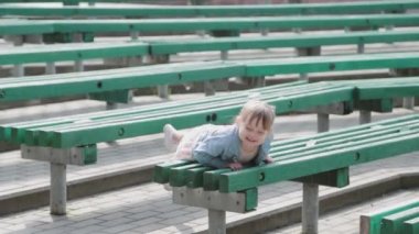 Küçük mutlu kız tahta banklarda sürünüyor..