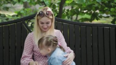 Parkta kollarında küçük kızı olan mutlu genç bir anne..