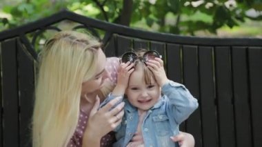 Parkta kollarında küçük kızı olan mutlu genç bir anne..