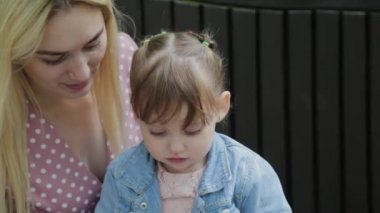 Parkta kollarında küçük kızı olan mutlu genç bir anne..