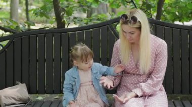 Küçük kızı olan genç bir anne parkta güvercinleri besliyor..