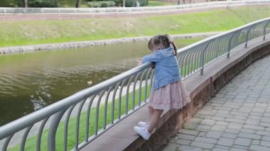 Küçük mutlu kız, korkulukların yanında yürür..