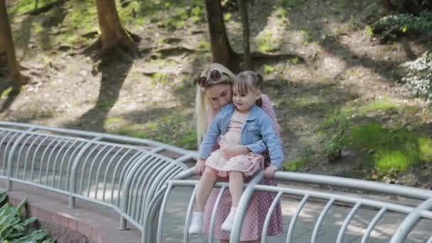 Glückliches kleines Mädchen spaziert mit junger Mutter am Geländer entlang. — Stockvideo