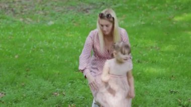 Genç anne ve küçük kızı güneşli havada parkta eğleniyorlar..