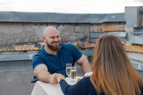 Verliebte auf dem Dach sitzen an einem Tisch mit Champagner. — Stockfoto