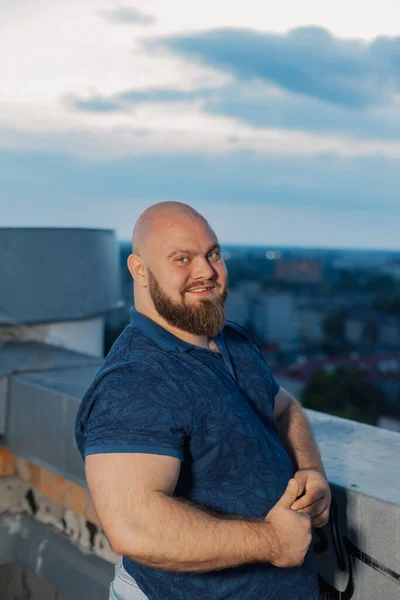 Grande bodybuilder barbuto sul tetto la sera. — Foto Stock