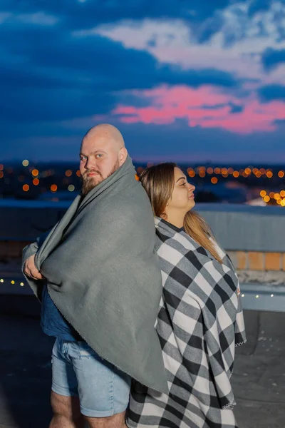 Hermosa pareja en el techo bajo una manta en la noche. —  Fotos de Stock