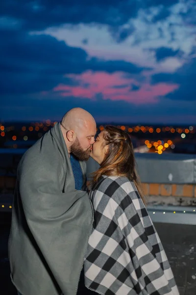 Beautiful couple on the roof under a blanket in the evening. — Stock Photo, Image