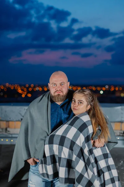 Hermosa pareja en el techo bajo una manta en la noche. —  Fotos de Stock