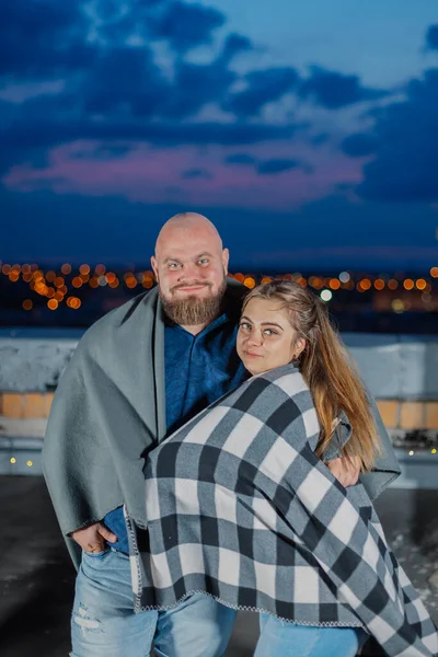 Belo casal no telhado sob um cobertor à noite. — Fotografia de Stock
