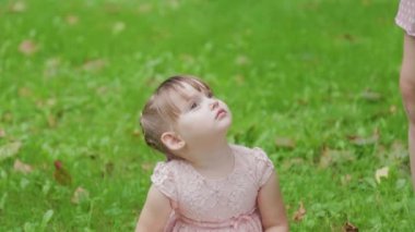 Parkta çimlerin üzerinde cep telefonuyla konuşan güzel küçük kız..