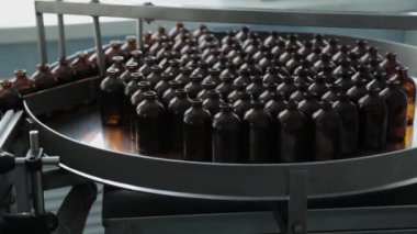 Kahverengi tıbbi şişeler bir uyuşturucu üretim tesisinde taşıyıcı bantta..