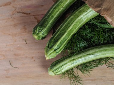 Üç yeşil biyolojik sebzeli sebzeyi açık kahverengi bir masa ve fotokopi alanı olan geri dönüşümlü bir kağıt torbanın üzerinden çekiyoruz.
