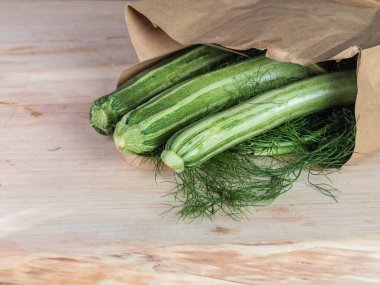 Üç yeşil biyolojik sebzeli sebzeyi açık kahverengi bir masa ve fotokopi alanı olan geri dönüşümlü bir kağıt torbanın üzerinden çekiyoruz.
