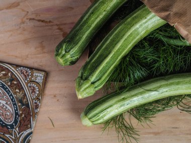 Üç yeşil biyolojik sebzeli sebzeyi açık kahverengi bir masa ve fotokopi alanı olan geri dönüşümlü bir kağıt torbanın üzerinden çekiyoruz.