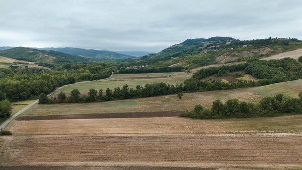 Живописный деревенский вид на Rolling Hills и культурный флигель в итальянском городке Вернаска под облачным небом недалеко от Сан-Джентео в итальянской провинции Вернаска