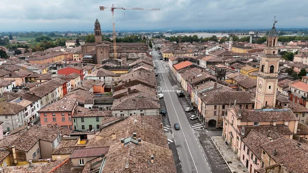 Cortemaggiore insansız hava aracı tarihi İtalyan kasabası Emilia Romagna şehir manzarası fayanslı çatıları ve bulutlu gökyüzü altındaki kilise çan kulesi