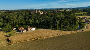 Tarihi Rivalta Manastırı yakınlarındaki altın buğday hasadı, hava aracı perspektifi güneşli Parma, İtalya 'da yeşillik ve yuvarlanan kırsal alanları ortaya çıkarıyor