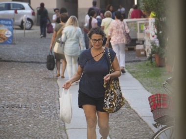 Cremona, İtalya - 3 Eylül 2025 Bir kadın alışveriş torbaları taşıyan güneşli bir yaz gününde İtalya 'nın Cremona şehrinde yürüyor