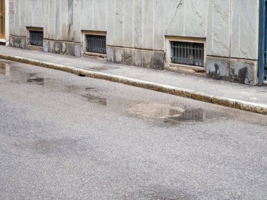 Yağmurdan sonra asfalt bir sokağa pencere inşa etmenin yansımaları kaldırım yüzeyinde ilginç soyut desenler ve dokular oluşturur.