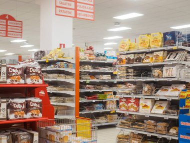 Cremona, İtalya 10 Eylül 2025 Güzel stoklanmış süpermarket koridorunda çeşitli paketli yiyecekler, abur cuburlar ve parlak, davetkar bir yerde pişmiş yiyecekler var.