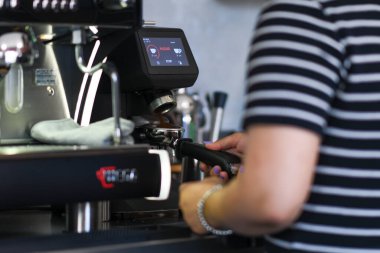 Cremona, İtalya 19 Temmuz 2025 Barista profesyonel bir Wega Polaris kahve makinesiyle kahve hazırlıyor, sabah bir İtalyan barında bir portafilyuma taze demlenmiş espresso döküyor.