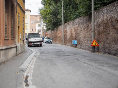 Cremona, İtalya 16 Eylül 2025 Suzuki Vitara ve Fiat Strada araçları eski tuğladan bir duvarla dar bir şehir sokağında yol işaretleri göstererek tarihi bir yolda 30 derece hız sınırı koyuyorlar.