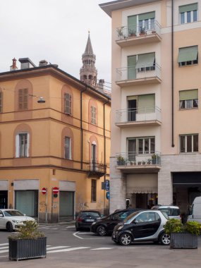 Cremona, İtalya 16 Eylül 2025 Parma şehir merkezi sokak köşesi bulutlu gökyüzü altında tarihi binaları ve modern yerleşim binalarını gösteriyor, arabalar çalışıyor ve ortaçağ Torrazzo çanı
