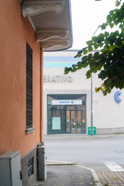 Cremona, İtalya - 21 Eylül 2025 Kentsel sokak sahnesinde cam kapılı bir bina girişi ve yukarıda görünen bazı harfler ve çerçevenin sol tarafında turuncu bir duvar yer alıyor.