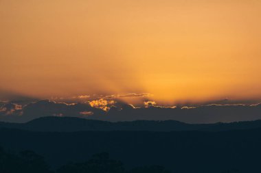 Sunshine Coast hinterland üzerinde gün batımı. Güneş bulutların arkasına kaybolur gibi izliyoruz altın ışınları ateşe bulutlar kırılgan kenarlarına olduğunu.