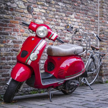 Kırmızı scooter ve bir bisiklet vintage duvara yakın: