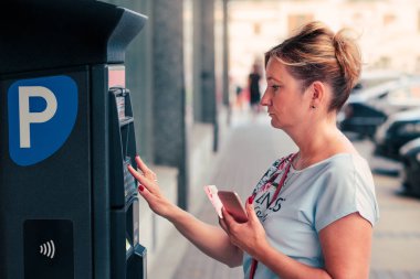 Kadın Park kullanmak için bir bilet satın alma kartı veya cep telefonu, Park makine yanında duran borç